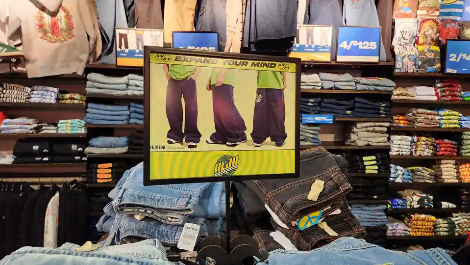 A retail store display features a prominent sign advertising 'ACAB' jeans with the slogan 'EXPAND YOUR MIND' above images of…