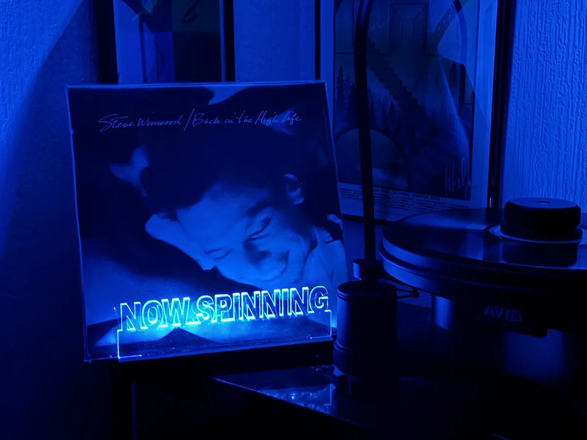 A vinyl record player with an 'AVID' brand turntable is shown under blue lighting, next to the album cover for 'Steve…