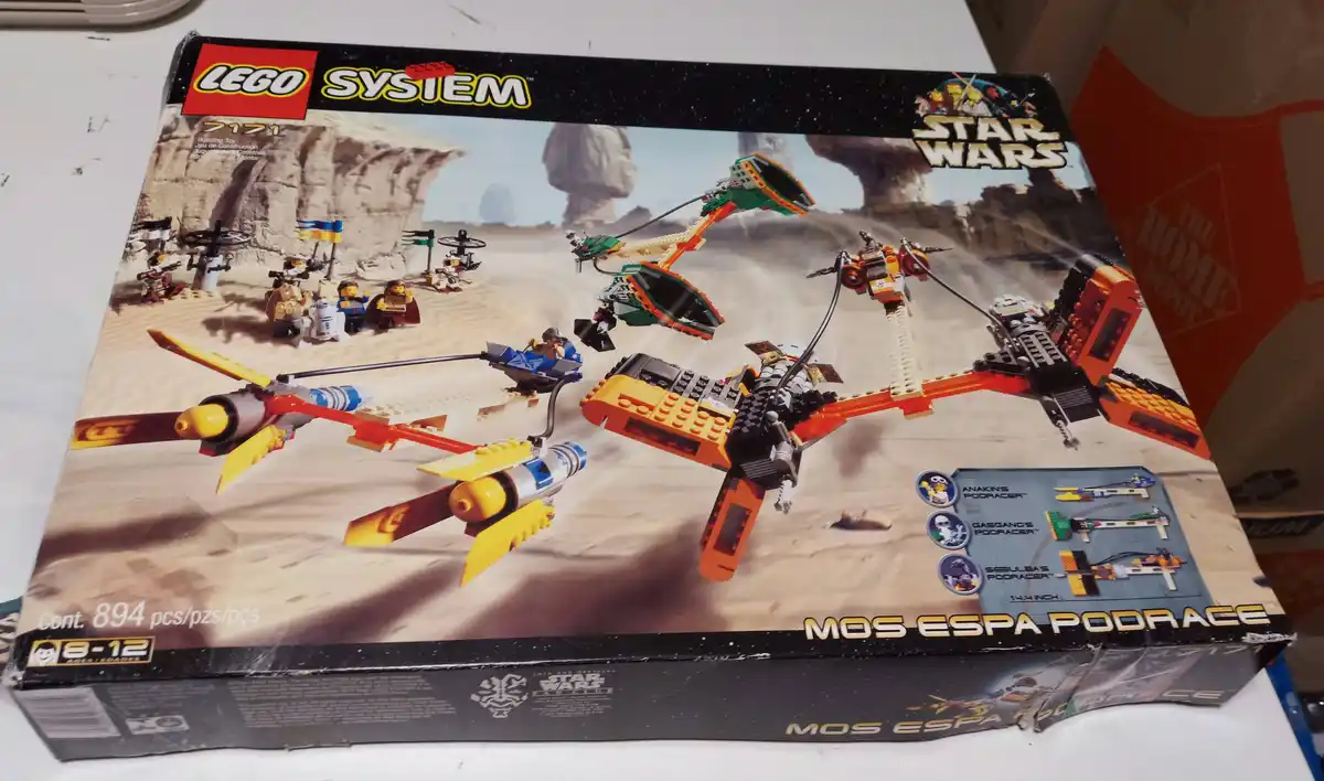 The image shows a worn LEGO Star Wars set box for 'Mos Espa Podrace' (set #7171), depicting three LEGO podracers racing…
