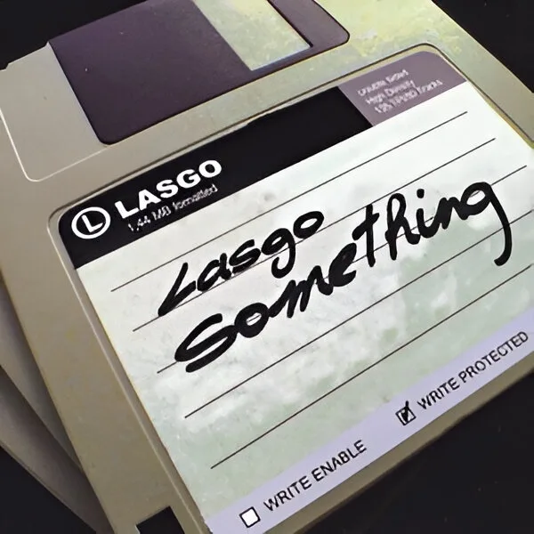 A close-up of a beige 3.5-inch floppy disk with a handwritten note on its label that reads 'Lasgo Something'. The disk's…