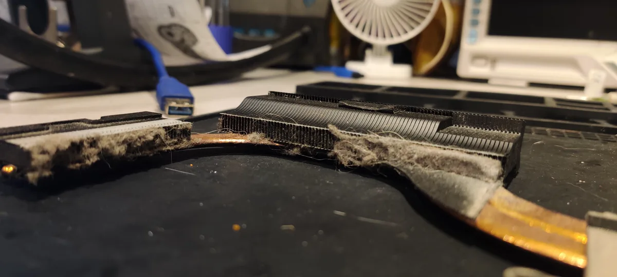A close-up photo shows a heavily clogged laptop heatsink with dust and debris, resembling a dirty weapon. The text overlay…