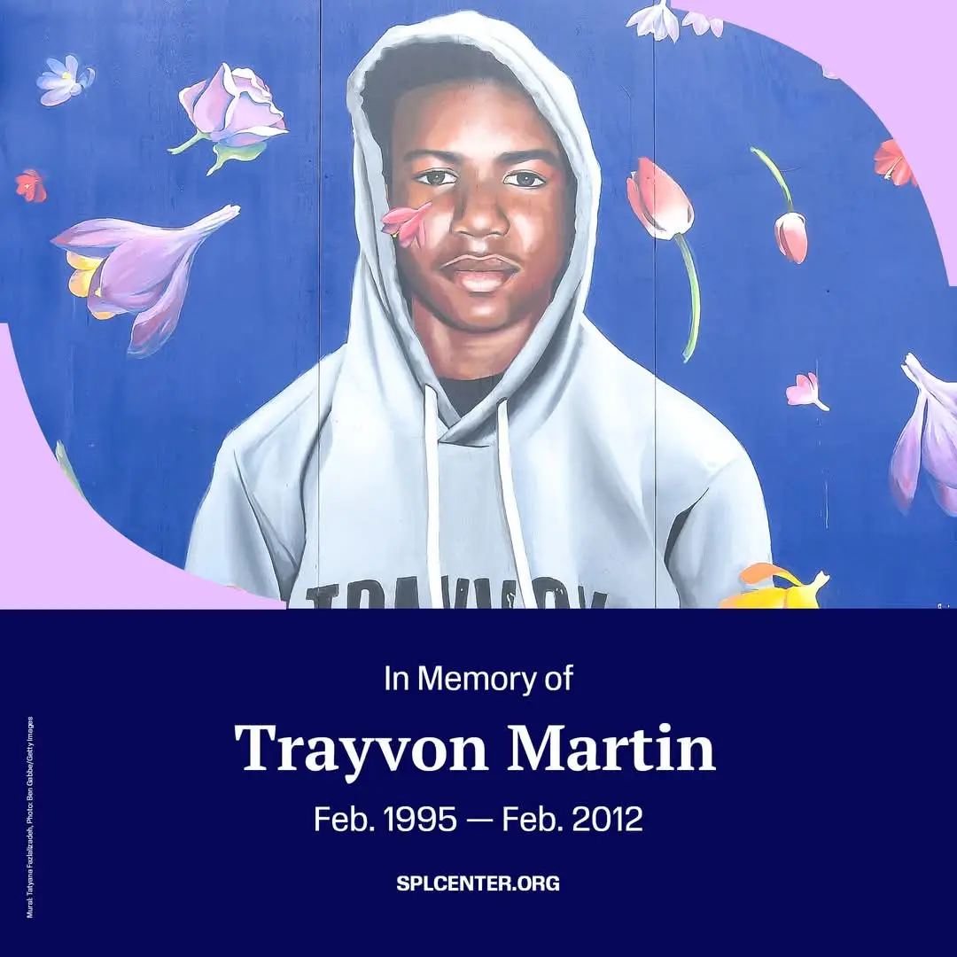 A mural depicts a young Black man in a light gray hoodie against a blue background with floating pink and purple flowers…