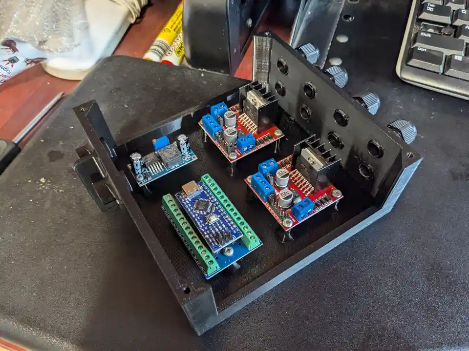 A close-up photo shows a black 3D-printed enclosure containing several electronic circuit boards, including a blue Arduino…