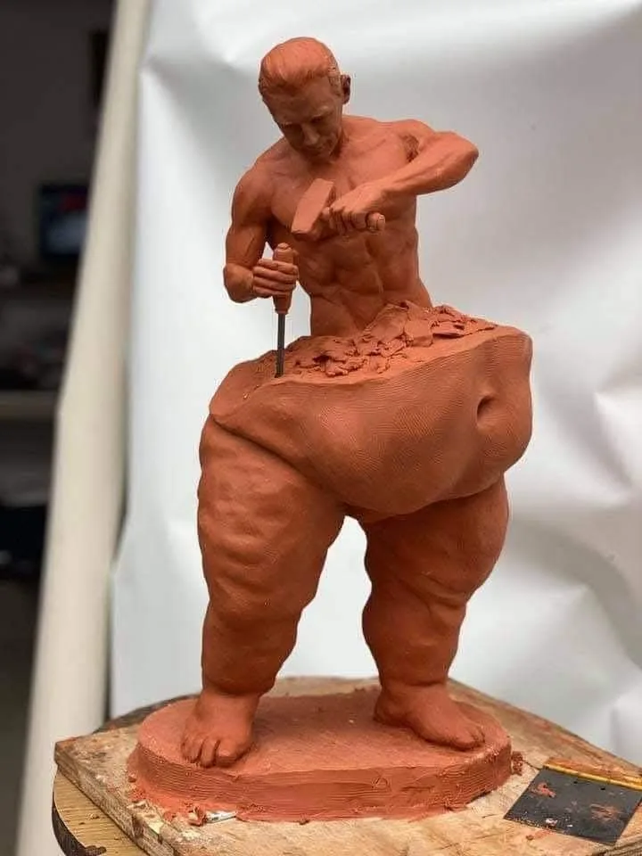 A clay sculpture of a muscular man actively chiseling away at his own buttocks with a mallet and chisel, while the text…