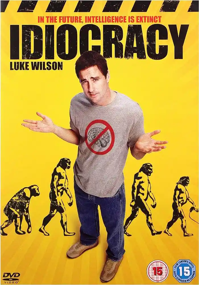 A movie poster for 'Idiocracy' featuring actor Luke Wilson standing with arms outstretched, wearing a grey t-shirt with a…