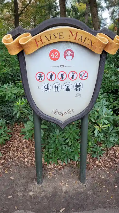 A shield-shaped sign with a yellow banner reading 'HALVE MAEN' at the top, displaying various icons including a red circle…