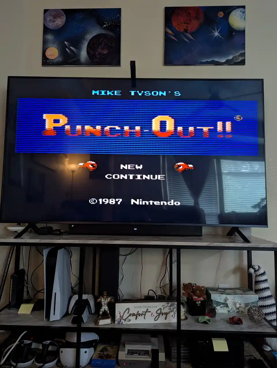 A television displays the title screen of the classic 1987 Nintendo game 'Mike Tyson's Punch-Out!!' with 'NEW' and…