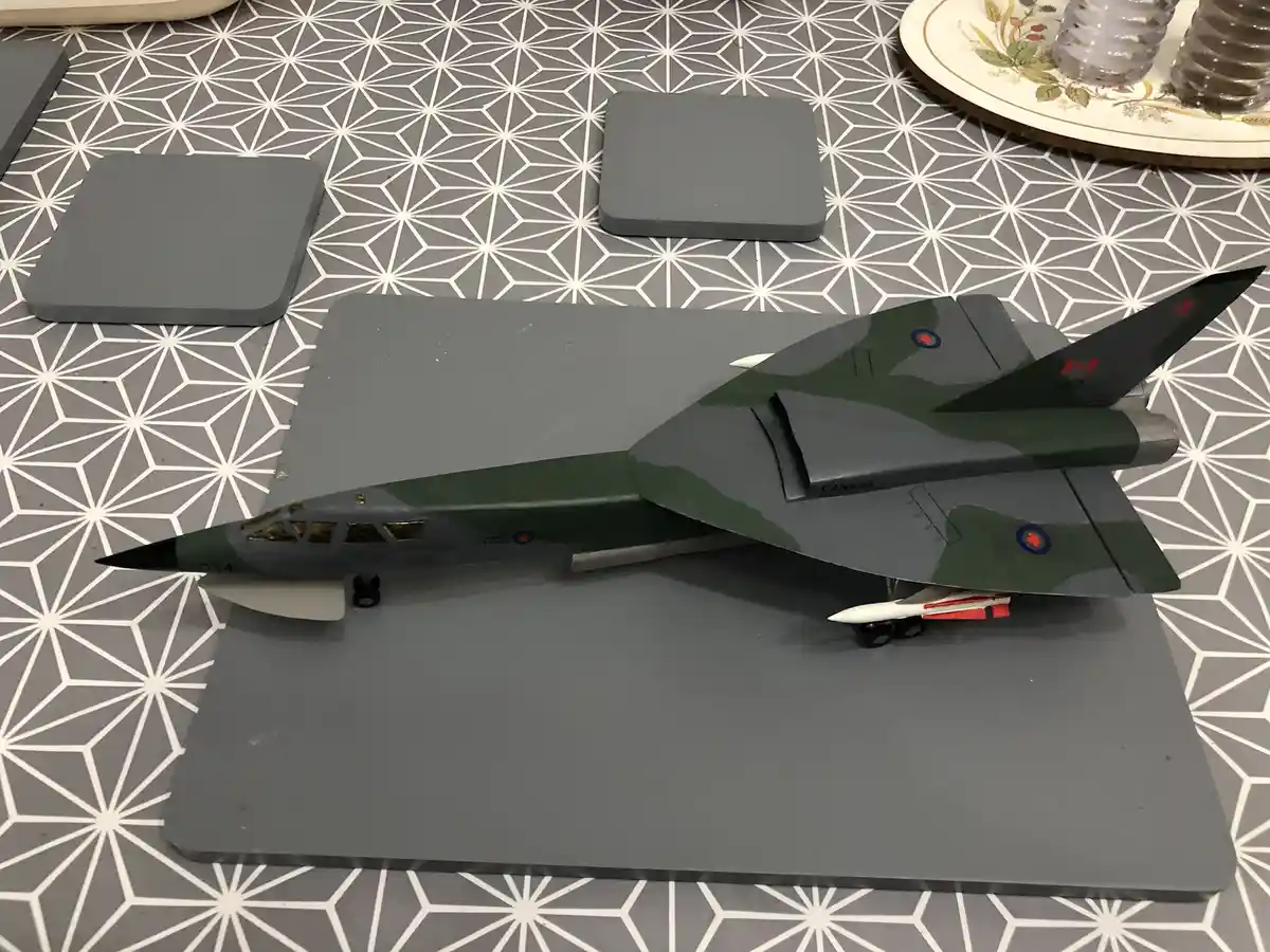 A model of a Canadian military jet, painted in green and grey camouflage with 'CANADA' written on its side, sits on a grey…
