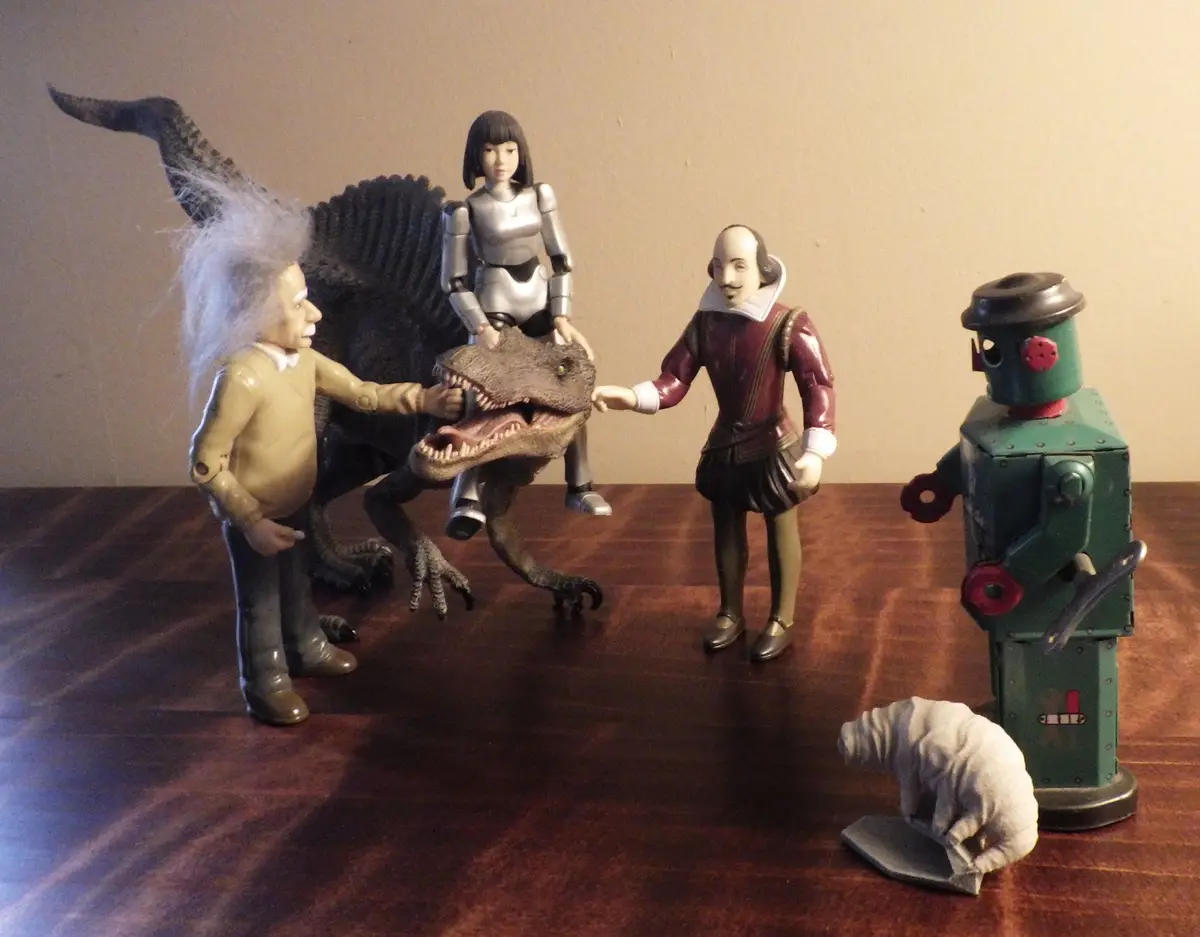 A staged photo of toy figurines: Albert Einstein, William Shakespeare, a female armored figure riding a Spinosaurus, a…
