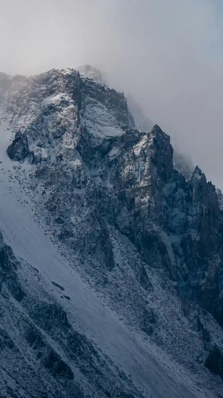 A dramatic, misty mountain peak covered in snow and rock, with a dark, moody atmosphere. Overlaid text reads 'i'm not lazy…