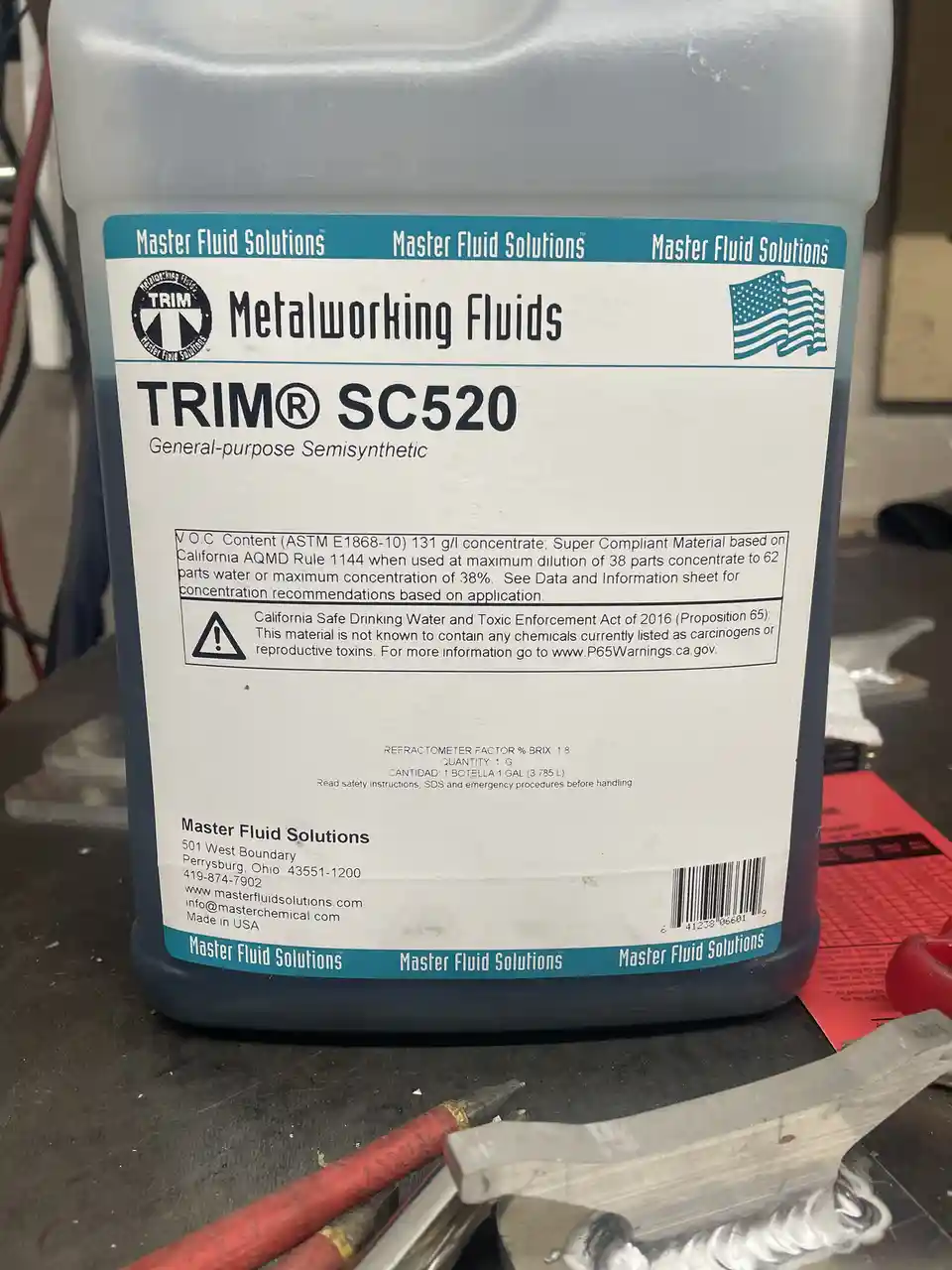 A close-up photo of a gray plastic jug labeled 'TRIM® SC520 General-purpose Semisynthetic' from Master Fluid Solutions…