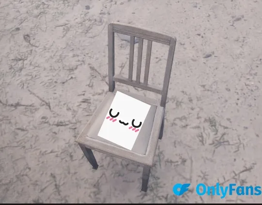 A simple wooden chair sits alone on a sandy, grass-strewn ground. On the seat is a white square with a cute, smiling cartoon…