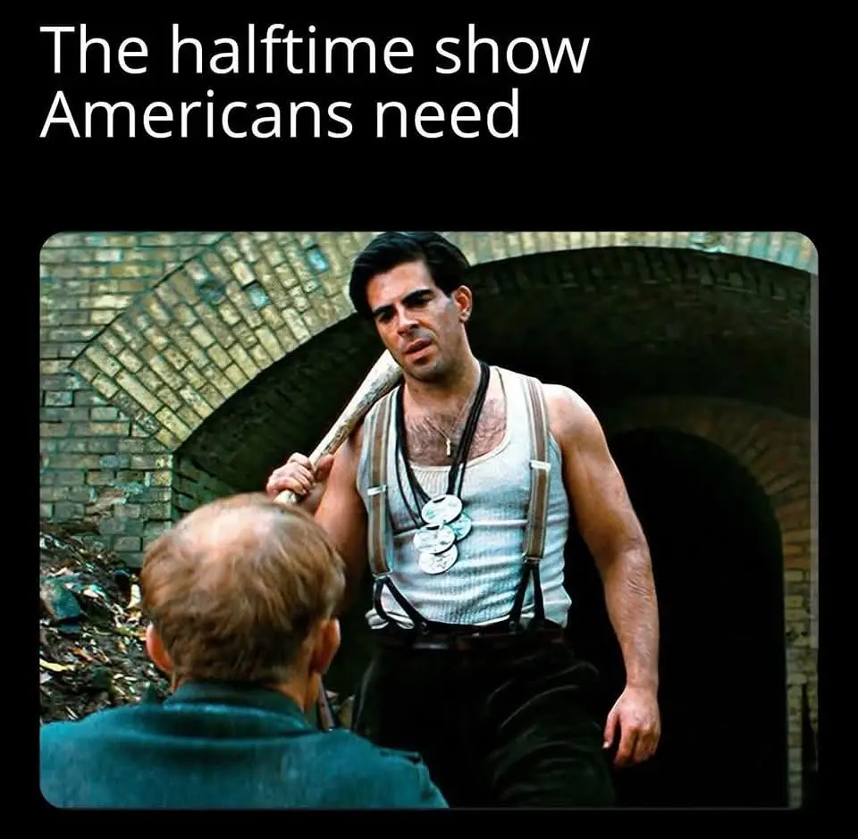 A man with a baseball bat over his shoulder stands menacingly in front of another man, who is seen from behind. The man with…
