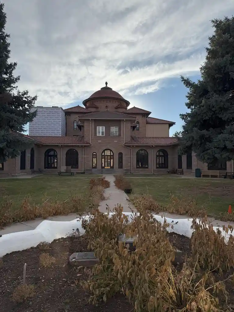 A large, ornate stone building with a red-tiled dome and arched windows is partially covered in construction insulation…