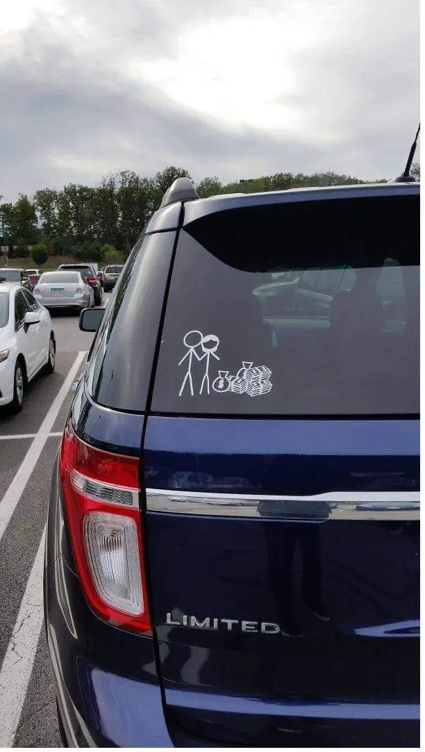 The image shows the rear of a dark blue Ford Explorer Limited parked in traffic. A white sticker on the rear window depicts…