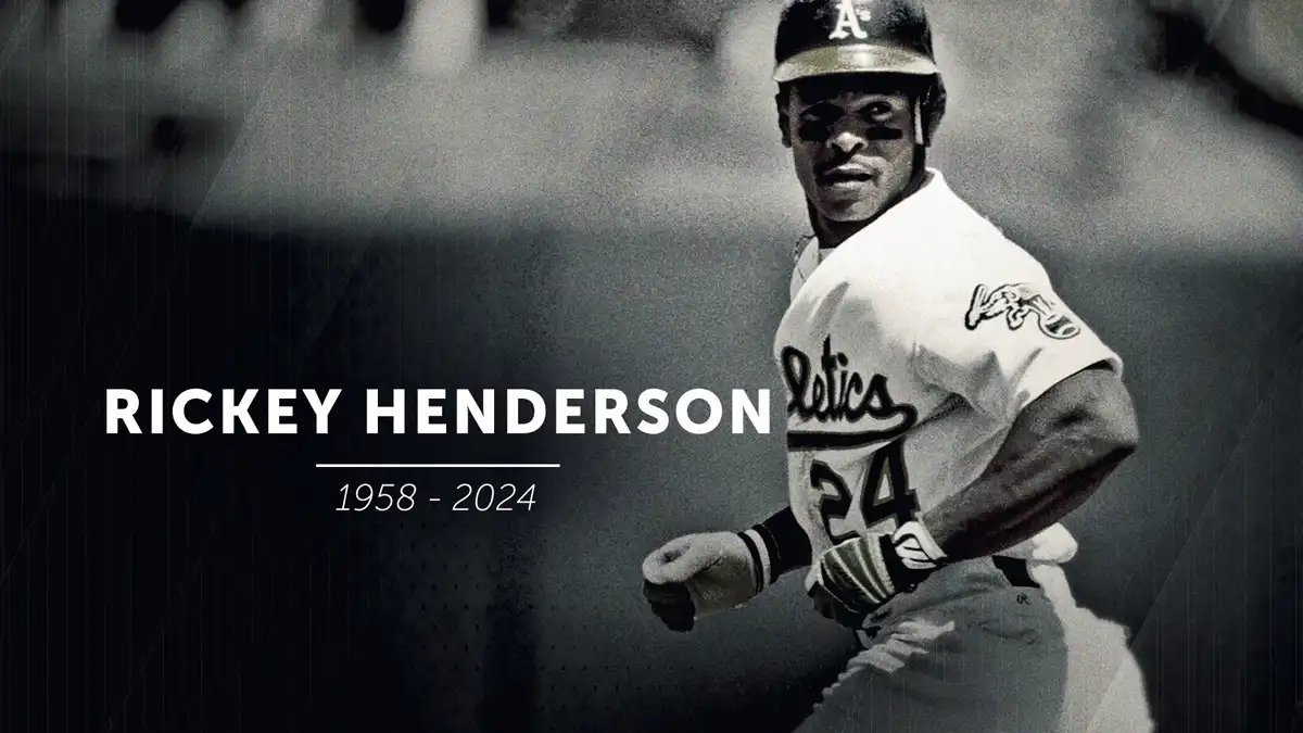 A black and white photo of baseball player Rickey Henderson in an Oakland Athletics uniform, running with a determined…
