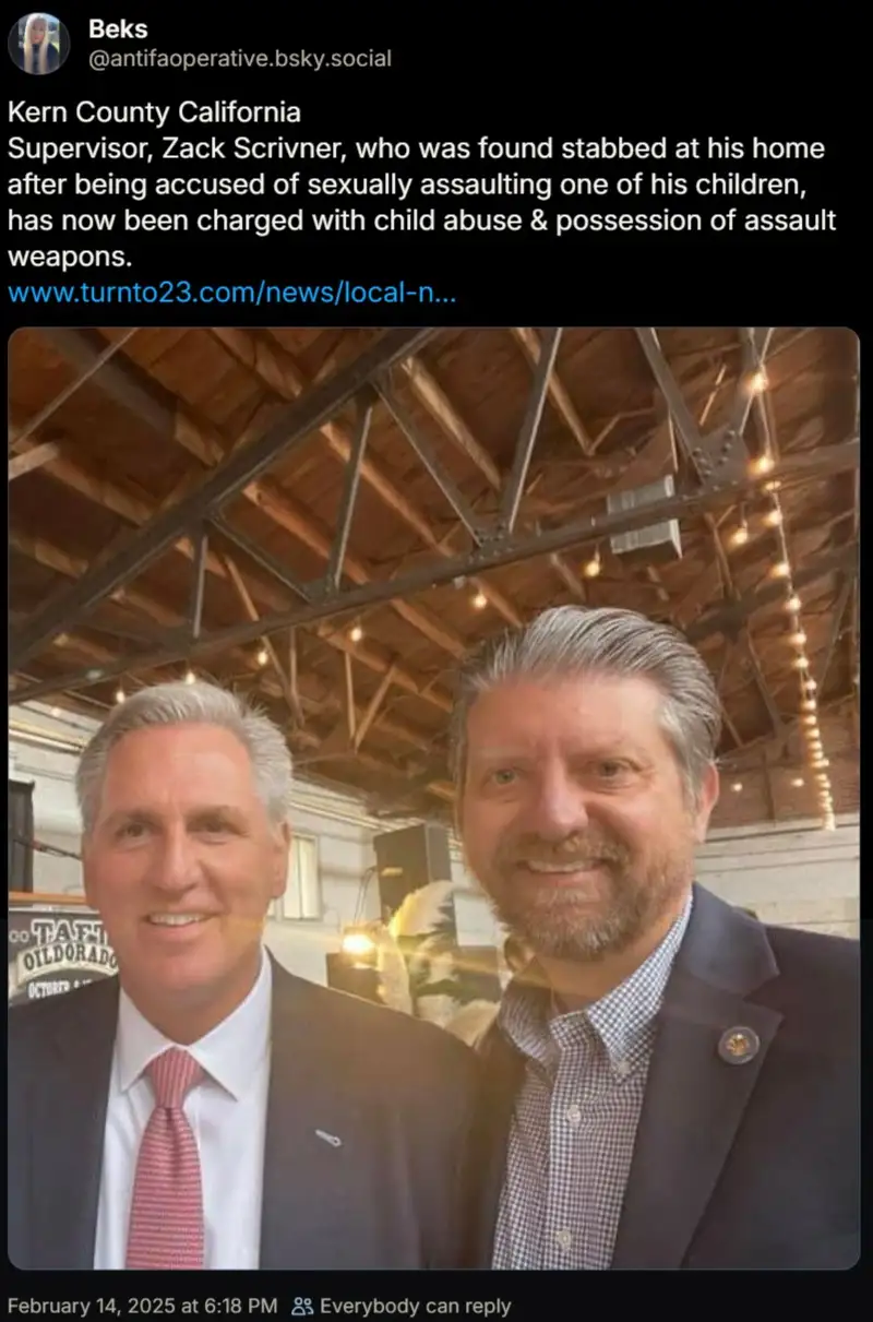 A screenshot of a social media post showing two smiling men in suits posing for a photo under a wooden-beamed ceiling with…