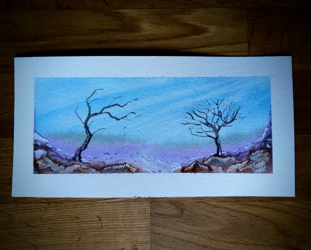 A watercolor painting on textured paper shows two bare, leafless trees standing on rocky ground under a gradient sky of blue…