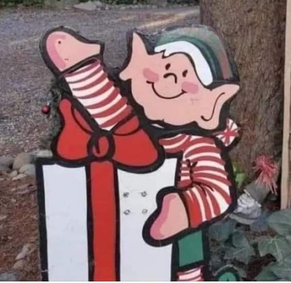 A cutout of a smiling cartoon elf in red-and-white striped clothing and a green hat is shown holding a large white gift box…