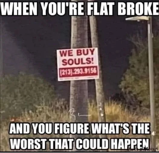 A nighttime photo shows a white sign with red text on a utility pole that reads 'WE BUY SOULS!' and includes a phone number…
