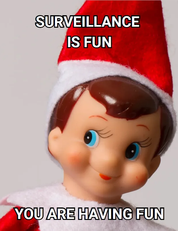 A close-up of a plastic elf doll wearing a red and white Santa hat, smiling with rosy cheeks and large blue eyes. White bold…