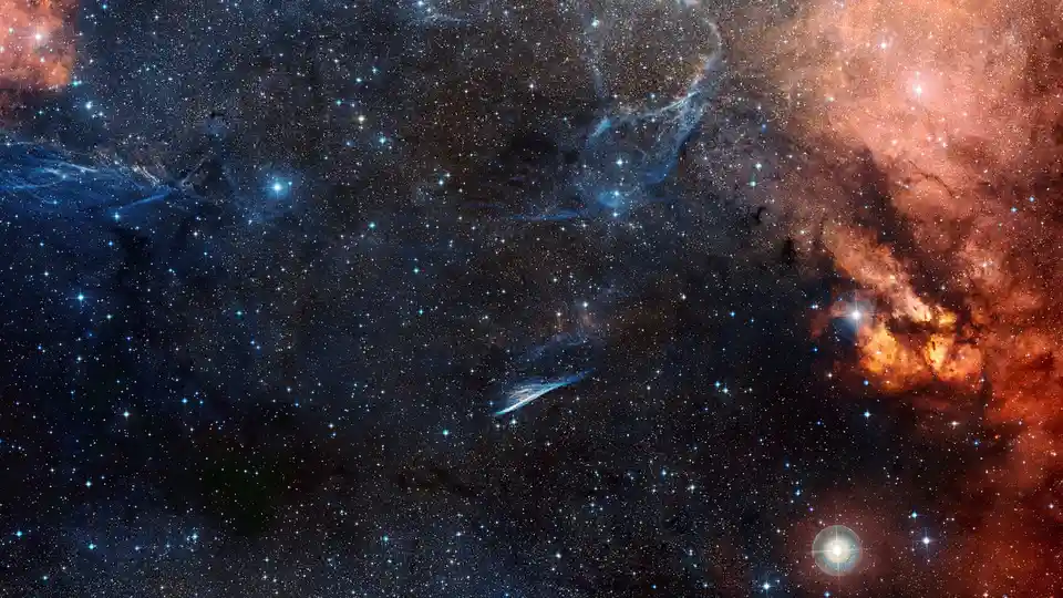 A cosmic space image filled with countless stars, glowing blue and orange nebulae, and dark cosmic dust clouds. The overlaid…