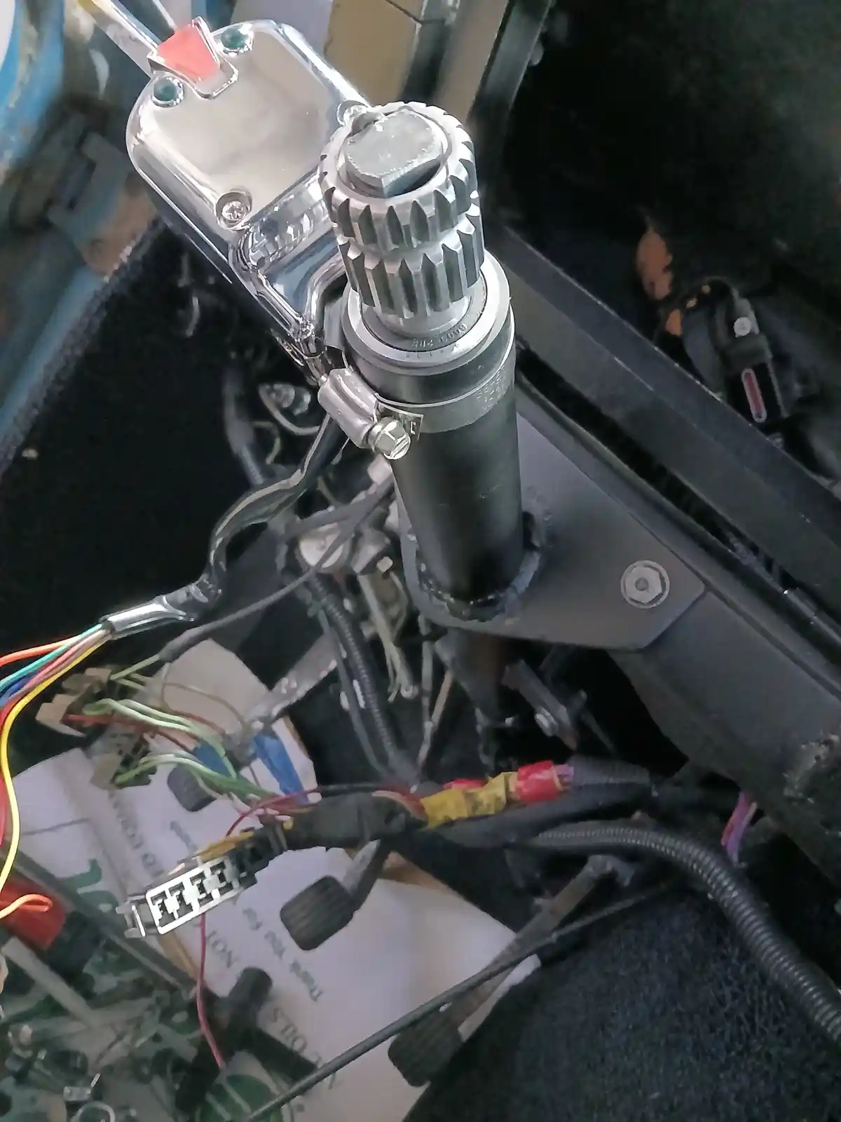 A close-up photo shows a motorcycle's gear shifter assembly with a chrome gear lever and surrounding wires and components…