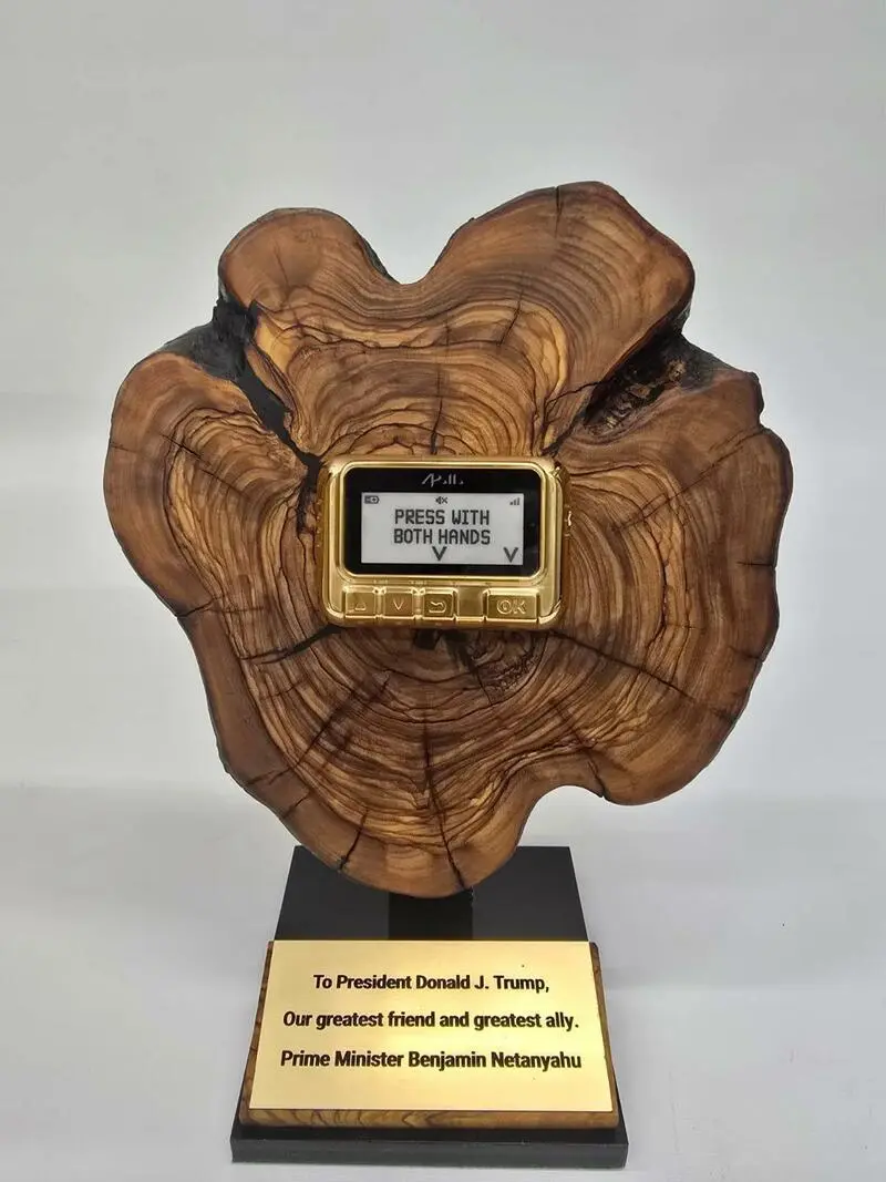 A wooden trophy with a gold-framed digital screen embedded in its center displays the text 'PRESS WITH BOTH HANDS' with…