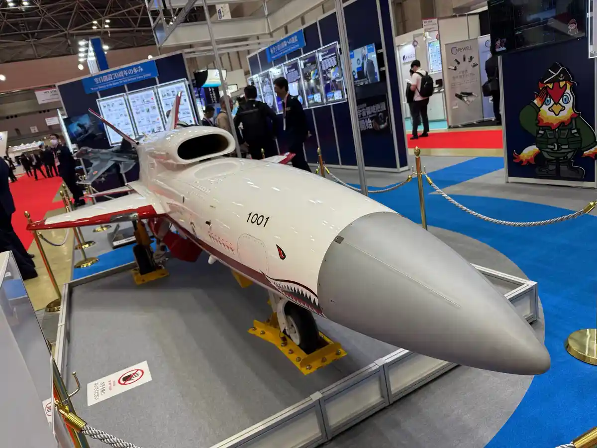 A white and red Japanese fighter jet model, marked with the number 1001 and a shark mouth design, is displayed at a military…