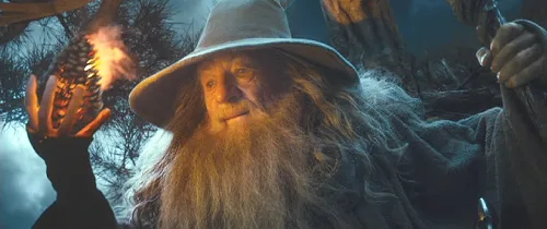 A close-up of Gandalf the Grey from 'The Lord of the Rings' holding a flaming pinecone in one hand and a staff in the other…