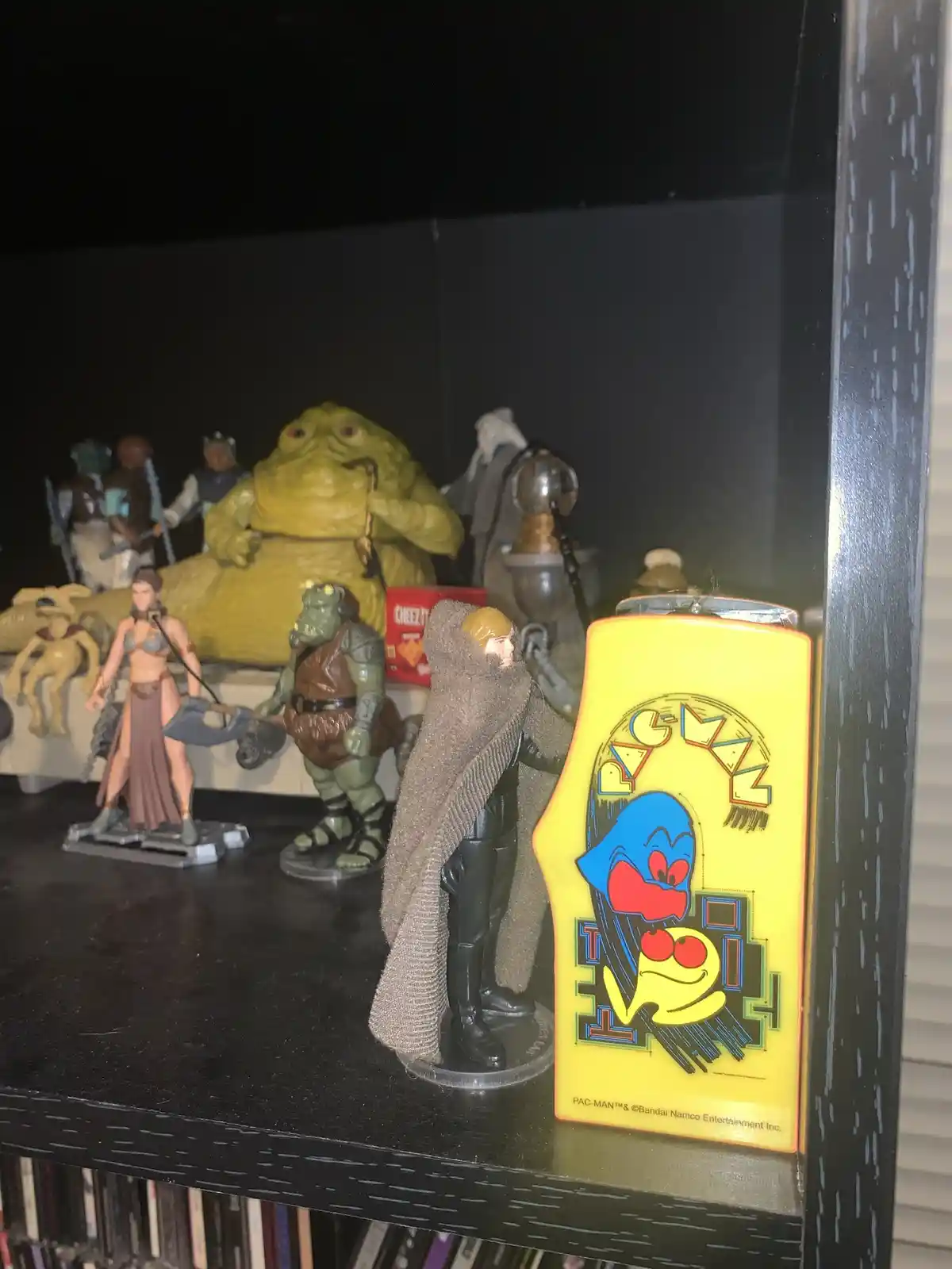 A shelf displays various action figures, including Jabba the Hutt, a Stormtrooper, and a character in a brown cloak…