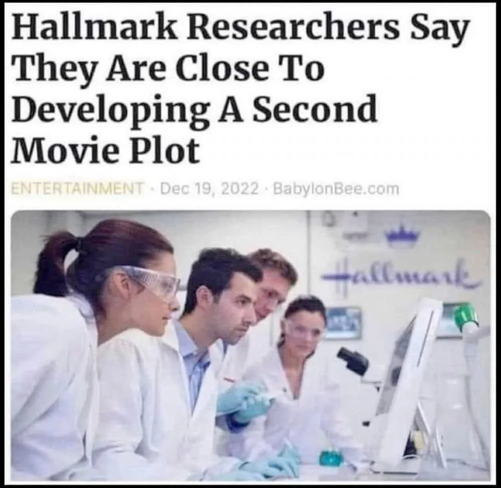 A group of scientists in white lab coats and safety goggles are gathered around a computer in a lab, with the 'Hallmark'…
