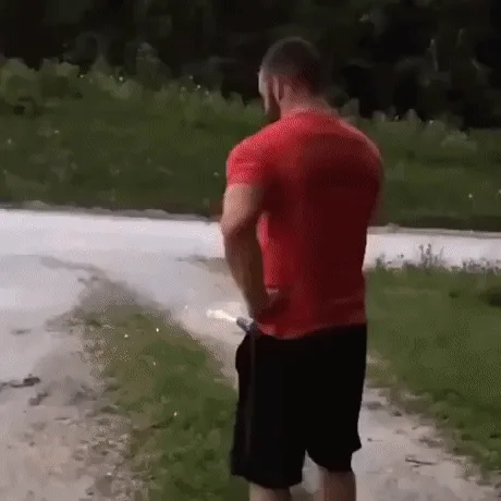 A man in a red t-shirt with the text 'DO IT BECAUSE I SAID SO' is shown holding a firework that shoots sparks and smoke. He…
