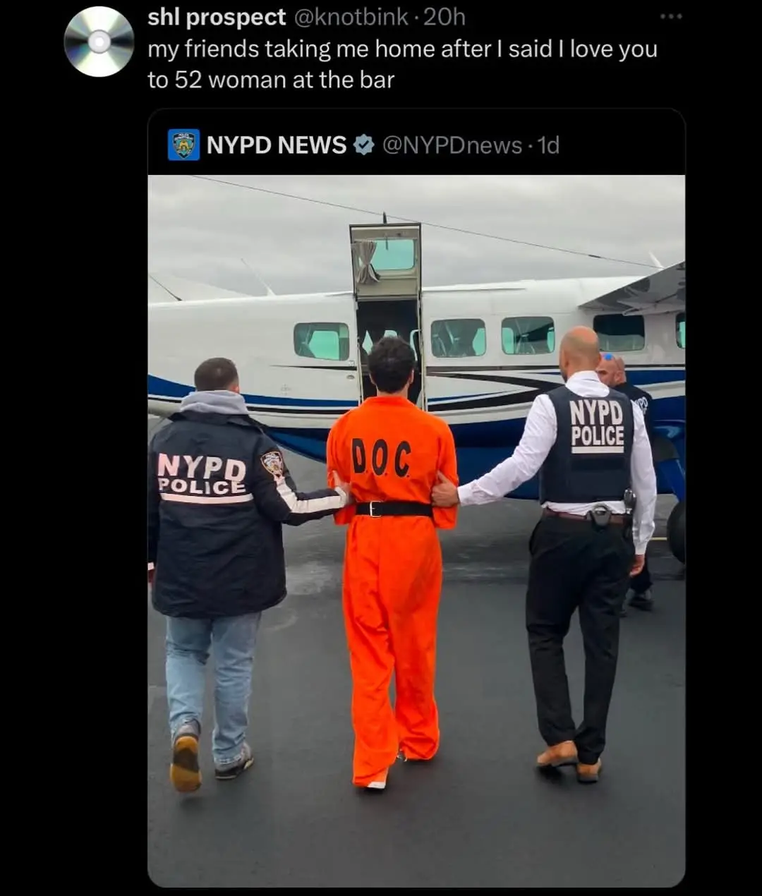 Two NYPD police officers are escorting a person in an orange jumpsuit labeled 'D.O.C.' toward a small private airplane. The…