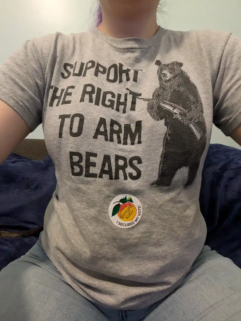 A person wearing a gray t-shirt with bold black text reading 'SUPPORT THE RIGHT TO ARM BEARS' and an illustration of a bear…