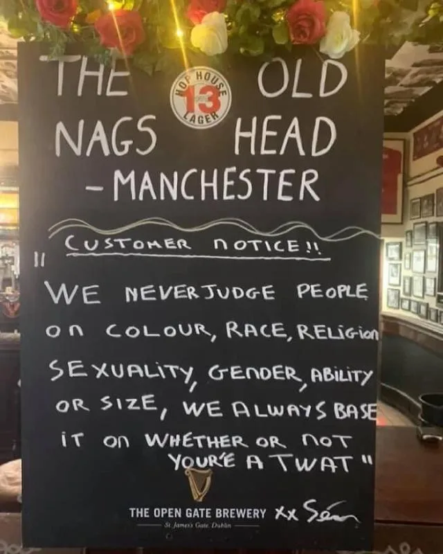 A black chalkboard sign in a pub named 'The Nags Head - Manchester' displays a 'Customer Notice!!' that humorously states…