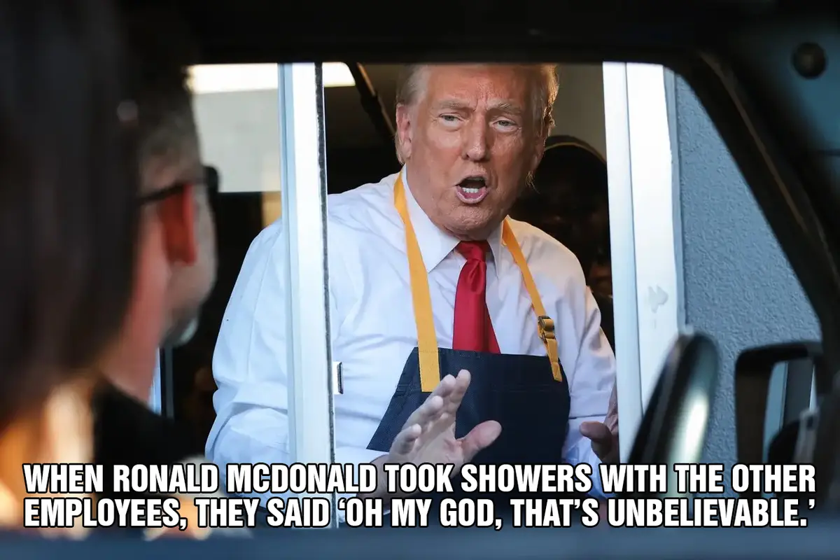 A man resembling Donald Trump, wearing a white shirt, red tie, and a McDonald's apron, is seen leaning out of a vehicle…