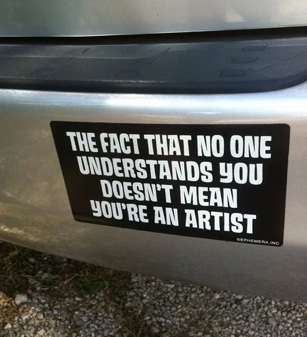 A black rectangular sticker with bold white text is affixed to the rear bumper of a silver vehicle. The text reads 'THE FACT…