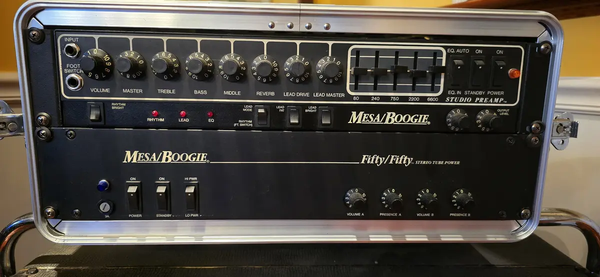 A close-up of a Mesa/Boogie 'Fifty/Fifty' stereo tube guitar amplifier head, showing its complex control panel with numerous…