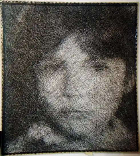A square artwork with a dense, chaotic web of black threads covering a faint, ghostly portrait of a person's face, with the…
