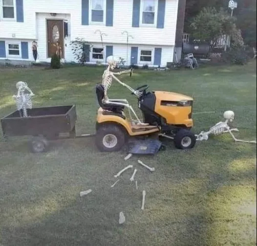 A yellow riding lawn mower is being driven by a skeleton, with another skeleton pulling it from behind using a rope and a…