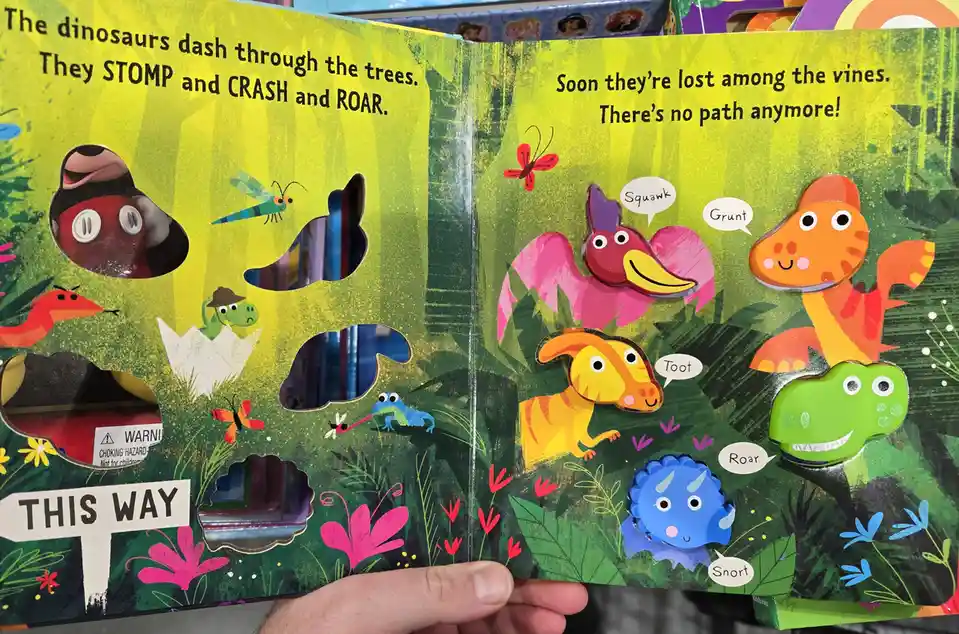 A colorful children's pop-up book page shows cartoon dinosaurs in a jungle, with text describing their chaotic movement. The…