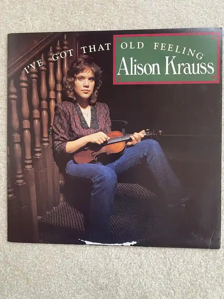 A vintage album cover of Alison Krauss sitting on stairs holding a violin, with the title 'I'VE GOT THAT OLD FEELING' arched…