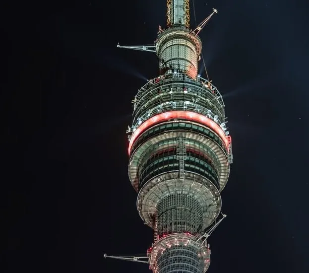 A nighttime low-angle photo of the Sydney Tower Eye, showing its illuminated structure against a dark sky. The tower appears…