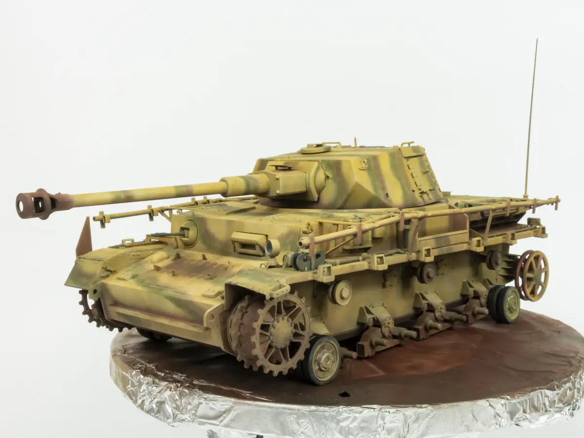 A highly detailed, painted model of a German World War II tank, likely a StuG III, is displayed on a round cake stand. The…