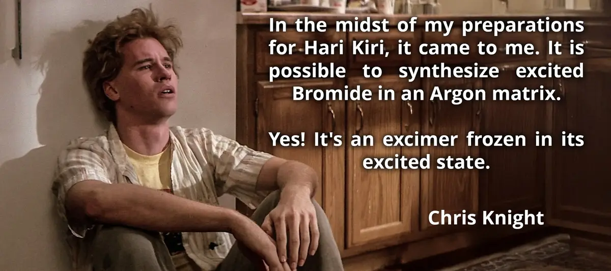 A man with messy hair sits against a wall next to wooden cabinets, looking upward with a thoughtful expression. Overlaid…