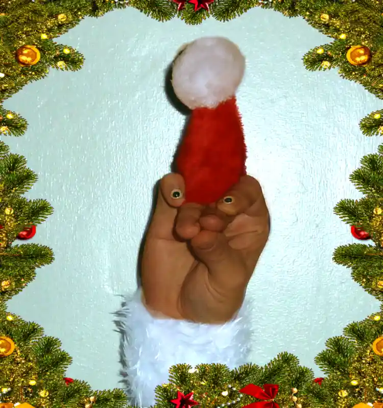 A human foot is shown wearing a miniature red Santa hat with a white pom-pom, framed by a decorative Christmas wreath with…