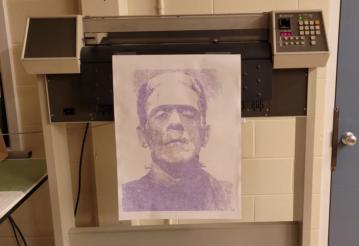 A vintage-looking plotter printer outputs a purple dot-matrix portrait of Frankenstein's monster, but the image is…