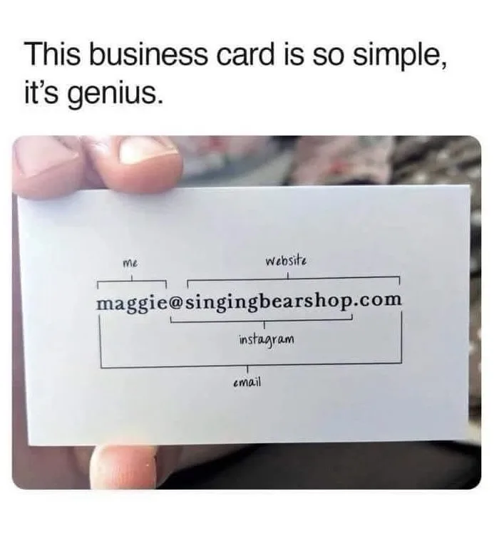 A hand holds a plain white business card with handwritten text. The card displays 'maggie@singingbearshop.com' as the main…