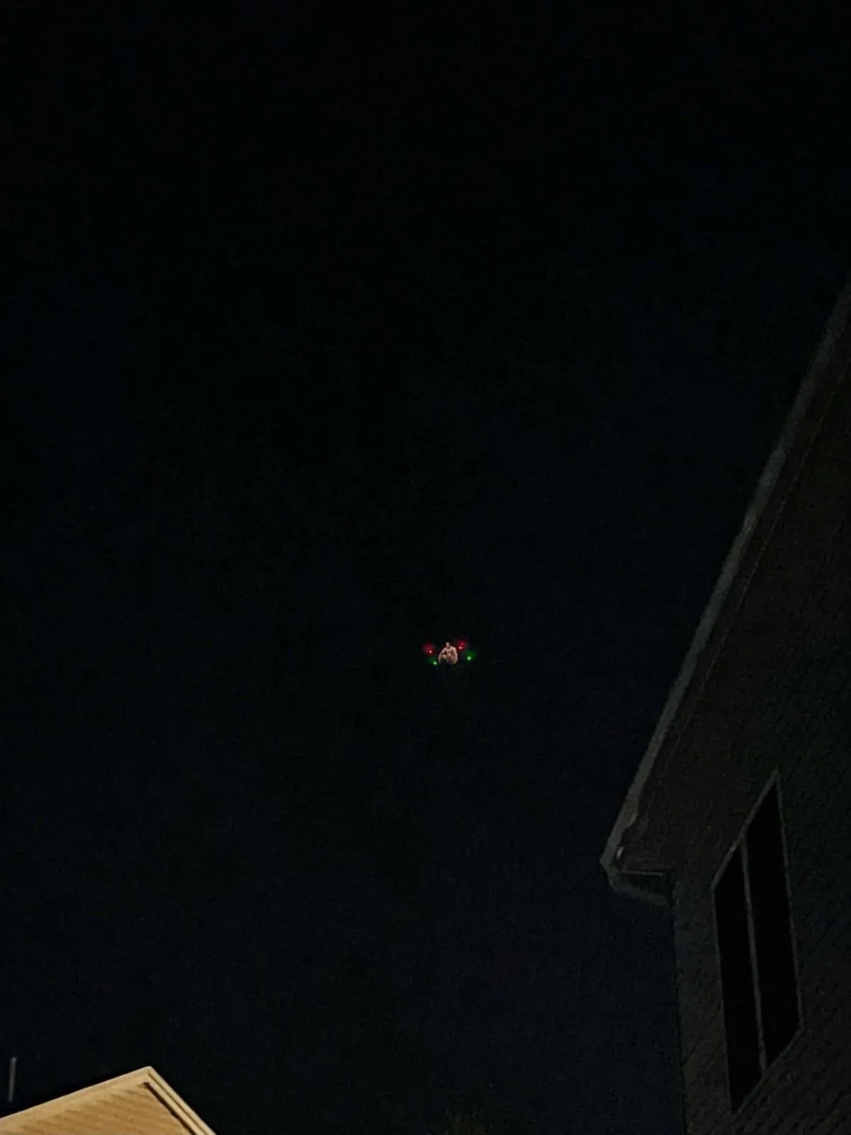 A dark night sky above rooftops shows a small drone with red and green lights hovering. The overlaid text reads 'i think i…